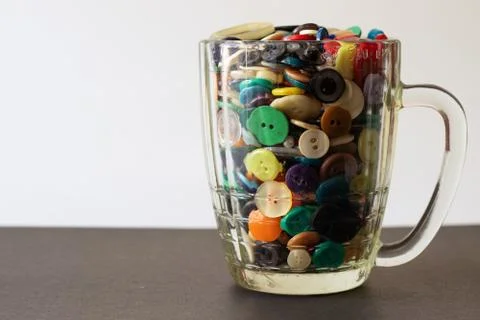 A lot of multi-colored buttons for clothes in a beer mug. Foto stock