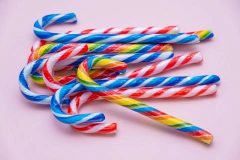 Lot of multi-colored candy canes on a pink background, copy space Stock Photos