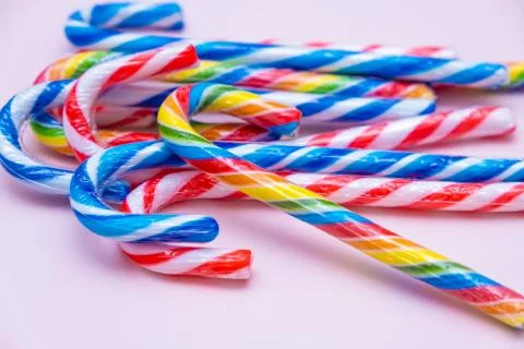 Lot of multi-colored candy canes on a pink background, copy space Stock Photos
