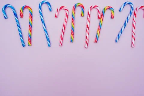 Lot of multi-colored candy canes on a pink background, copy space Stock Photos