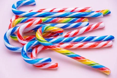 Lot of multi-colored candy canes on a pink background, copy space Stock Photos