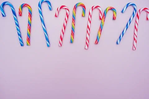 Lot of multi-colored candy canes on a pink background, copy space Stock Photos