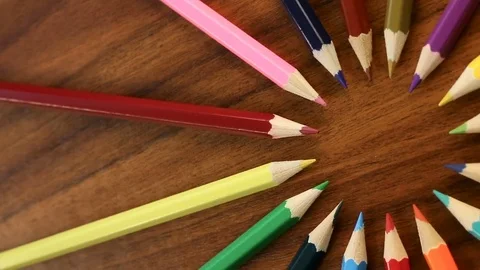 A lot of multicolored pencils revolve in a circle on a black wooden backgro.. Stock Footage 76449368