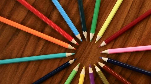 A lot of multicolored pencils revolve in a circle on a black wooden backgroun Stock Footage 84414844
