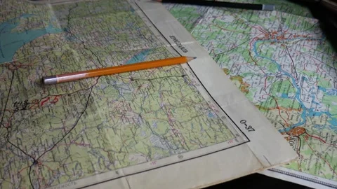 A lot of old maps on the black table. Old phone, notebook, pencils Stock Footage 102228139