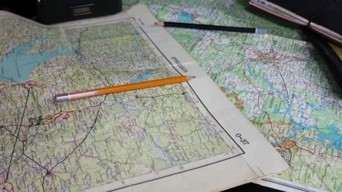 A lot of old maps on the black table. Old phone, notebook, pencils Stock Footage 102228143