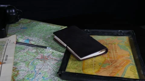 A lot of old maps on the black table. Old phone, notebook, pencils Stock Footage 102228367