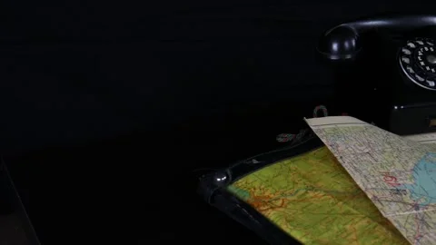 A lot of old maps on the black table. Old phone, notebook, pencils Stock Footage 102228380