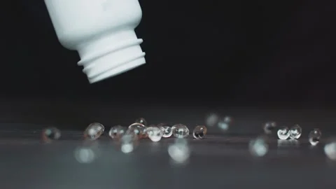 A lot of pills in gelatin capsules dropped on the dark surface from the bottle Stock Footage 162500341