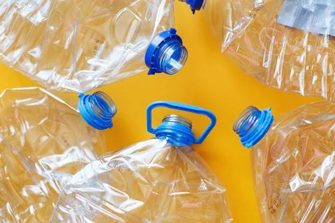 A lot of plastic empty rumpled used bottles on a yellow background. waste and Foto stock