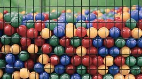 A lot of plastic multi-colored round balls of the same size behind the bars Stock Footage 86047629