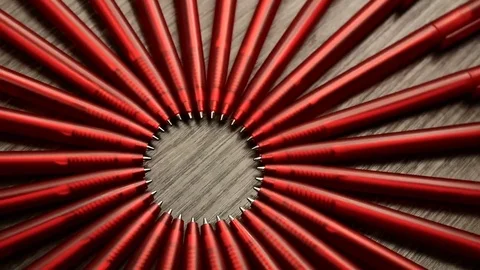 A lot of red pens move in a circle on a black wooden background. Concept offi Stock Footage 77876904