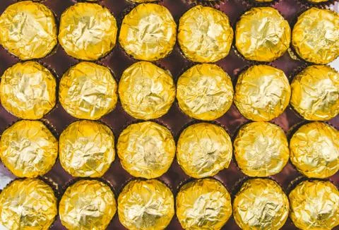 A lot of shiny golden chocolate wrapper in line on white background. Stock Photos