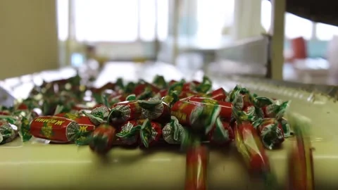 A lot of sweets move along the conveyor falling from top to bottom. Stock Footage 128643244