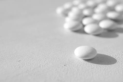 A lot of white round tablets lying on a white background. side view Stock Photos