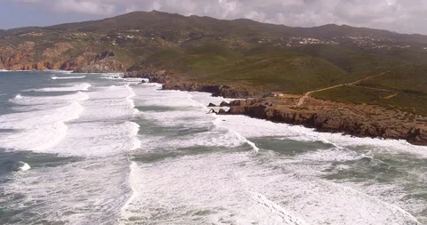 Lots of big strong waves hitting cliff with a house Stock Footage 87539168