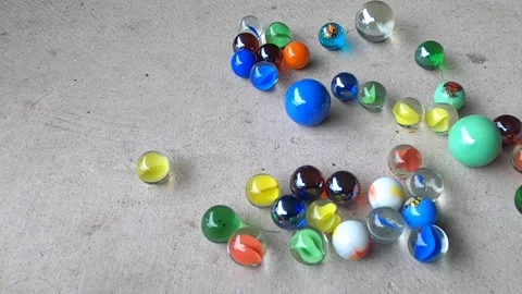 Lots of bright rolling marbles collide on a concrete floor in slow motion. Stock Footage 169146839