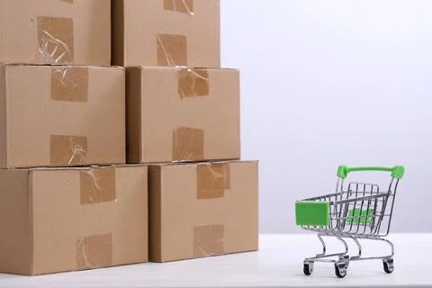 Lots of cardboard boxes on the table and a mini shopping cart. The concept of Stock Photos