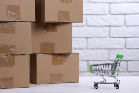 Lots of cardboard boxes on the table and a mini shopping cart. The concept .. Stock Photos