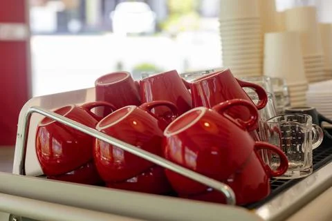 Lots of ceramic red coffee cups on espresso machine shelf in coffee shop. Sel Stock Photos