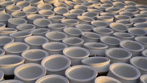 Lots of clay pots painted white, drying outside on the ground in the evening sun Stock Footage 236412771