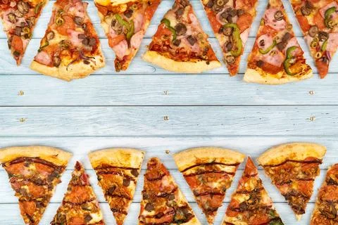 Lots of delicious triangular pizza slices on a blue wooden background 写真素材