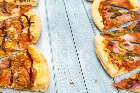 Lots of delicious triangular pizza slices on a blue wooden background 스톡 사진