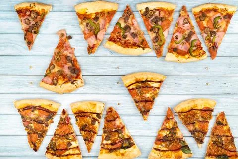 Lots of delicious triangular pizza slices on a blue wooden background Stock Photos