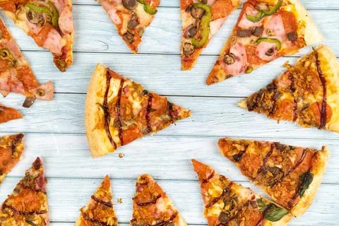 Lots of delicious triangular pizza slices on a blue wooden background Stock Photos