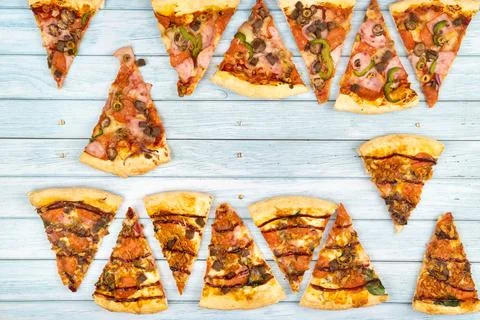 Lots of delicious triangular pizza slices on a blue wooden background Stock Photos