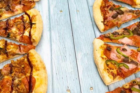 Lots of delicious triangular pizza slices on a blue wooden background 写真素材