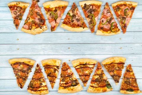 Lots of delicious triangular pizza slices on a blue wooden background Stock Photos