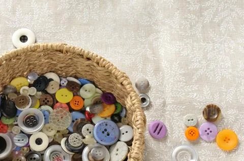 Lots of different colors and different shapes of buttons in a round straw basket Stock-Fotos
