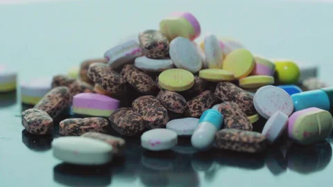 Lots of different types of pills on a white background turntable in slow motion. Stock Footage 240105835