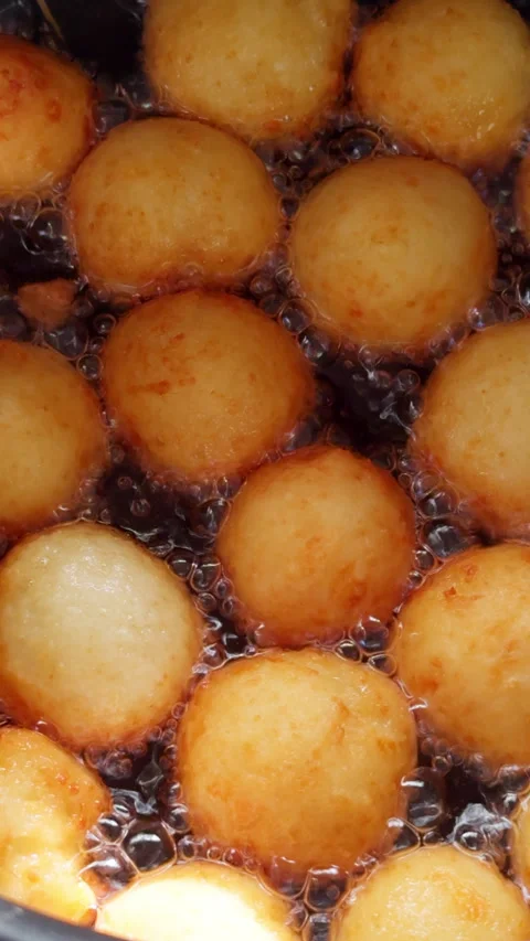 Lots of donuts with no hole in the middle are fried in oil deep. Stock Footage 279486083