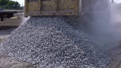 Lots of dust flying around while a dump truck is dumping crushed stone Stock Footage 160811738