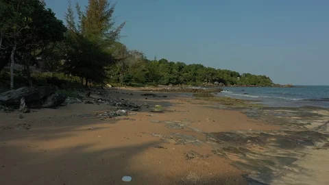 Lots of garbage on a beach and trash flying above by drone chasing dog running n Stock Footage 124326289