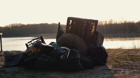 Lots of garbage, old stuff, on the beach at sunset. Environmental pollution. Video stock 115069259