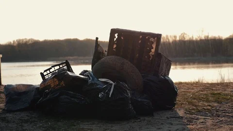 Lots of garbage, old stuff, on the beach at sunset. Environmental pollution. Video stock 115335572