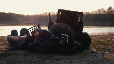 Lots of garbage, old stuff, on the beach at sunset. Environmental pollution. Video stock 115828784