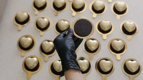 Lots of heart shaped cakes with gold color edible coating. Chef puts one to the Stock Footage 134345448