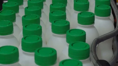 Lots of plastic bottles with milk and green caps move by conveyor Stock Footage 70486951