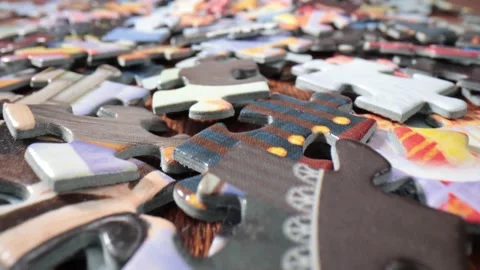 Lots of randomly placed puzzle pieces on a wooden table. Stock Footage 211399569