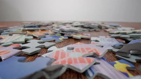 Lots of randomly placed puzzle pieces on a wooden table. Vídeo Stock 211399674