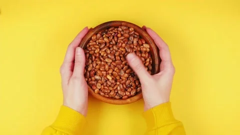 Lots of raw brown beans are spinning in a white plate close-up Stock Footage 166968680