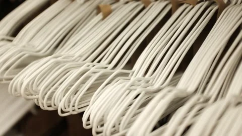 Lots of simple white empty hangers on a rack in a store. Minimalist home storage Stock Footage 320971587