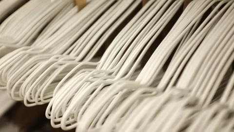 Lots of simple white empty hangers on a rack in a store. Minimalist home storage Stock Footage 320971814