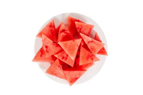 Lots of small triangular slices of ripe red watermelon on a plate. Isolated o Stock Photos