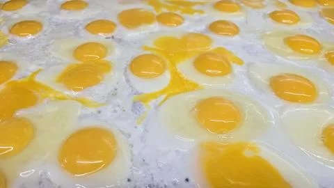 Lots of Sunny Side Up Fried Eggs Cooking at the grill Together For Breakfas.. Stock Photos