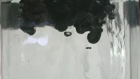 Lots of thick black ink falling down in clear water on a light background Stock Footage 291109143